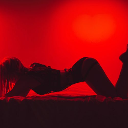 Fülledt BDSM erotikus jelenet a klub félhomályában, két alak közel egymáshoz, szenvedélyes hangulatban