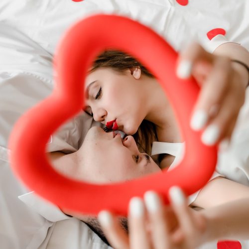 man and woman in love in bed with heart shaped confetti